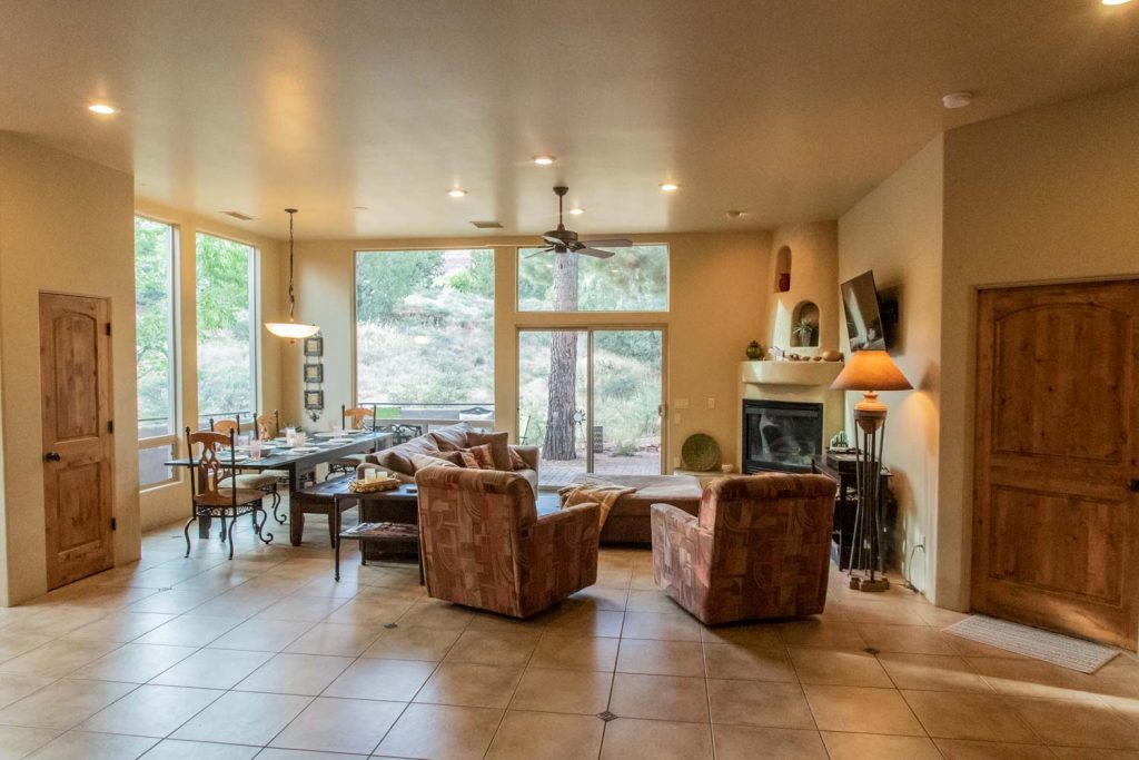 Spacious great room with flat screen TV, kiva-style fireplace, comfortable dining area and great views of the scenic, secluded backyard.